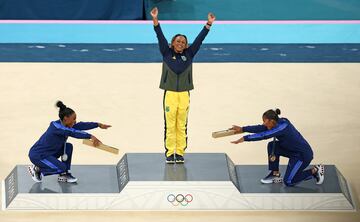 Jordan Chiles y Simone Biles del equipo de Estados Unidos homenajean a la medallista de oro Rebeca Andrade del equipo de Brasil en la ceremonia de entrega de medallas de gimnasia artística femenina.