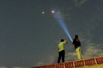 Imagen de dos hombres mirando a Marte junto con el eclipse lunar con luna de sangre 2018 desde Padang, en la isla de Sumatra, Indonesia.