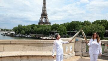 Torch bearers, Portuguese former marathon runner and Olympic champion Rosa Mota (L) and French author Elise Goldfarb pose on the Bir Hakeim bridge in front of the Eiffel Tower during the Olympic torch relay in Paris on July 15, 2024, ahead of the Paris 2024 Olympic and Paralympic Games. (Photo by ALAIN JOCARD / AFP)