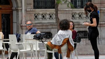 Varias personas se sientan en una terraza de un bar.