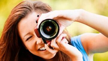 Chica sonriendo mientras hace una fotografía con su cámara de fotos.