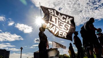 Una mujer sostiene una bandera Black Lives Matter durante un evento en memoria de George Floyd y para pedir justicia para aquellos que perdieron a sus seres queridos por la violencia policial fuera del Capitolio del Estado de Minnesota el 24 de mayo de 2021 en Saint Paul, Minnesota. 