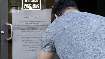 FILE - In this March 26, 2020 file photo a man takes a photo of a sign advising that the Employment Development Department is closed due to coronavirus concerns, in San Francisco. A review of California&#039;s unemployment agency has found its productivit