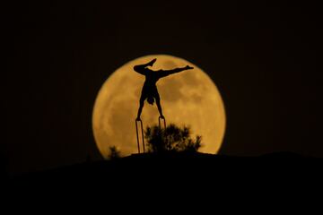 La luna llena detr¨¢s de la silueta de un hombre haciendo gimnasia en Erbil, Irak.