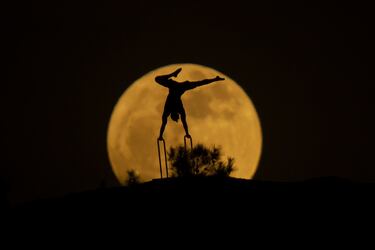 La luna llena detrás de la silueta de un hombre haciendo gimnasia en Erbil, Irak.