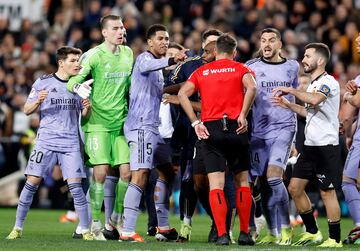 Los jugadores del Real Madrid protestan al árbitro del encuentro, Gil Manzano, tras la decisión de anular el gol a Jude Bellingham. En la imagen, el colegiado se lleva la  mano al bolsillo para sacar la tarjeta roja al jugador inglés.