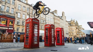 Danny MacAskill con su bici de MTB a punto de saltar desde una cabina roja de tel&eacute;fono de la Royal Mile en Edimburgo (Escocia, Reino Unido), con un Macbook Pro con carcasa Mous esper&aacute;ndole debajo. 
