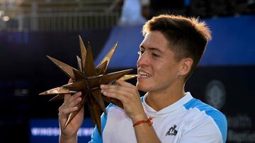 Sebastian Baez muerde el trofeo de campe¨®n del torneo de Winston Salem.