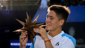 Sebastian Baez muerde el trofeo de campeón del torneo de Winston Salem.