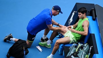 Carlos Alcaraz siendo atendido por un sanitario.