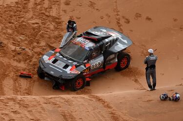 El piloto español de Audi Carlos Sainz (derecha) y el copiloto Luca Cruz inspeccionan su coche después de sufrir un accidente.
