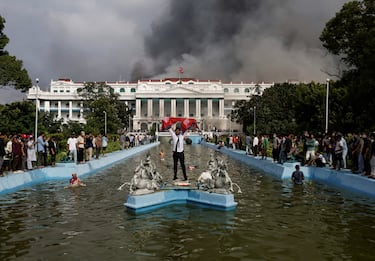 A demonstrator holding Nepal's flag celebrates at the Singha Durbar office complex that houses the Prime Minister's office and other ministries after storming it during a protest against Monday's killing of 19 people after anti-corruption protests that were triggered by a social media ban, which was later lifted, during a curfew in Kathmandu, Nepal, September 9, 2025. REUTERS/Navesh Chitrakar      TPX IMAGES OF THE DAY