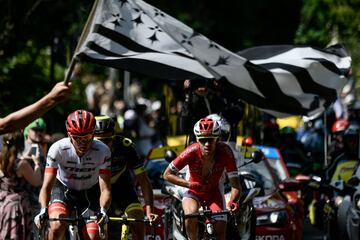 Un espectador agita la bandera de Bretaña sobre Toms Skujins de Letonia, Lilian Calmejane y Nicolas Edet de francia.