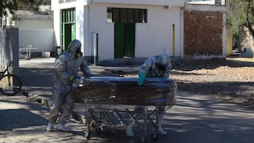 Workers transport the coffin of a COVID-19 victim to be buried in a common grave at the general cemetery in Cochabamba, Bolivia, on July 2, 2020. (Photo by DIEGO CARTAGENA / AFP)