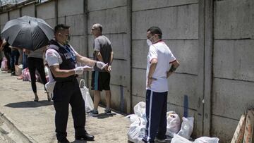 SJS01. SAN JOS&Eacute; (COSTA RICA), 20/04/2020. Un polic&iacute;a penitencial revisa los documentos a varias personas que hacen fila para ingresar en horas de visita a un centro penitenciario, este lunes en la provincia de Alajuela al oeste de San Jos&ea