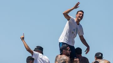 Argentina's players hold coach Lionel Scaloni as the team parades on board a bus after winning the Qatar 2022 World Cup tournament, in downtown Buenos Aires, on December 20, 2022. - Millions of ecstatic fans are expected to cheer on their heroes as Argentina's World Cup winners led by captain Lionel Messi began their open-top bus parade of the capital Buenos Aires on Tuesday following their sensational victory over France. (Photo by TOMAS CUESTA / AFP)