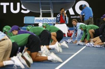 Kei Nishikori observa como los voluntarios y recogepelotas intentan secar la pista.