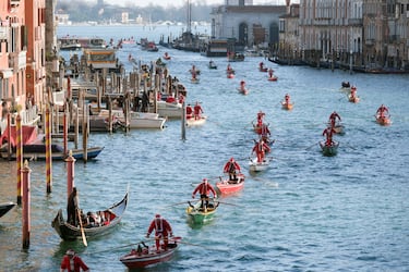 Personas vestidas de Papá Noel reman durantela  regata navideña en el Gran Canal de Venecia.