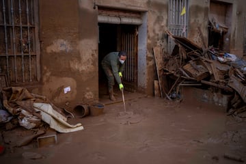 Un residente limpia su casa tras verse afectada por las inundaciones en Masanasa, Valencia. 