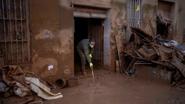 Un residente limpia su casa tras verse afectada por las inundaciones en Masanasa, Valencia.