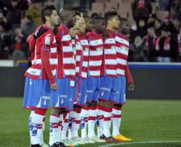 Los jugadores del Granada durante el minuto de silencio que se ha guardado en memoria de Luis Oruezábal 'Chikito', que falleció en su domicilio el pasado 31 de diciembre, esta noche al inicio del partido frente al Sevilla, de octavos de final de la Copa del Rey que se juega en el estadio Nuevo Los Cármenes, de Granada.