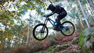 Cesar Sánchez saltando por una piedra en un circuito de MTB descenso de un bosque de Galicia construído por Roberto Bregua 'Troky', trail builder que construye los trails sin maquinaria.