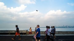 People wearing facemasks as a preventive measure against the Covid-19 coronavirus jog along the Marine Drive waterfront in Mumbai on September 30, 2020. (Photo by Jewel SAMAD / AFP)
