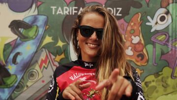 Una kitesurfista se&ntilde;ala a c&aacute;mara vestida con gafas de sol y la licra de competici&oacute;n de la Spain Kiteboarding League 2022 en el chiringuito El Tumbao, en la playa de Valdevaqueros (Tarifa, C&aacute;diz), el 16 de septiembre. 