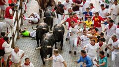 Participants run ahead of bulls during the "encierro" (bull-run) of the San Fermin festival in Pamplona, northern Spain on July 13, 2022. - On each day of the festival six bulls are released at 8:00 a.m. (0600 GMT) to run from their corral through the narrow, cobbled streets of the old town over an 850-meter (yard) course. Ahead of them are the runners, who try to stay close to the bulls without falling over or being gored. (Photo by MIGUEL RIOPA / AFP) (Photo by MIGUEL RIOPA/AFP via Getty Images)