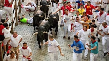 Participants run ahead of bulls during the "encierro" (bull-run) of the San Fermin festival in Pamplona, northern Spain on July 13, 2022. - On each day of the festival six bulls are released at 8:00 a.m. (0600 GMT) to run from their corral through the narrow, cobbled streets of the old town over an 850-meter (yard) course. Ahead of them are the runners, who try to stay close to the bulls without falling over or being gored. (Photo by MIGUEL RIOPA / AFP) (Photo by MIGUEL RIOPA/AFP via Getty Images)