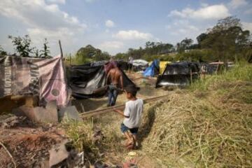Un hombre y hijo cargan madera para construir una vivienda improvisada en una área que fue ocupada por Integrantes del Movimiento de los Trabajadores Sin Techo (MTST) el pasado sábado situada a unos 4 kilómetros del estadio Arena Corinthians de Sao Paulo, una de las doce sedes del Mundial Brasil 2014 y que recibirá seis partidos del evento deportivo, entre ellos el inaugural del 12 de junio. De acuerdo con el movimiento, las familias que ocuparon el terreno, abandonado desde hace más de 20 años, vivían en áreas "de riesgo", "en favelas o sin condiciones para pagar el alquiler por culpa de la especulación inmobiliaria en la región, resultado de la construcción del estadio de apertura del Mundial".