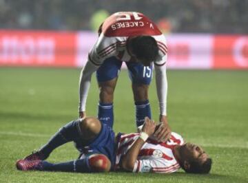 Paraguay's midfielder Victor Caceres (top) tries to help teammate Marcos Caceres during the Copa America third place football match against Peru in Concepcion, Chile on July 3, 2015.  AFP PHOTO / JUAN BARRETO