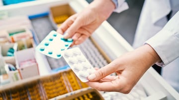 Pharmacists holding pills in hands above drawer with medicines. Close up of hands, unrecognizable person.