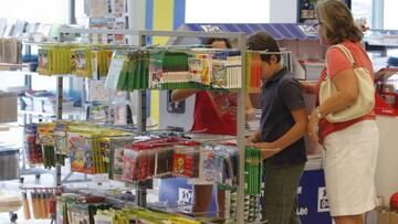 Vuelta al cole: ni&ntilde;os y mujer en la zona de art&iacute;culos escolares de un centro comercial