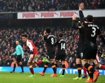 Arsenal's Chilean striker Alexis Sanchez (L) celebrates after scoring the opening goal as Hull players appeal for a hand ball against Sanchez during the English Premier League football match between Arsenal and Hull City at the Emirates Stadium in London on February 11, 2017. / AFP PHOTO / Glyn KIRK / RESTRICTED TO EDITORIAL USE. No use with unauthorized audio, video, data, fixture lists, club/league logos or 'live' services. Online in-match use limited to 75 images, no video emulation. No use in betting, games or single club/league/player publications. /