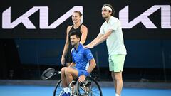 El tenista serbio Novak Djokovic, junto a Aryna Sabalenka y Stefanos Tsitsipas mientras prueba a disputar un punto en tenis en silla de ruedas en una exhibición previa al Open de Australia 2024.