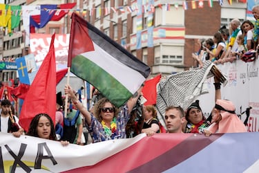 Unas personas muestran su apoyo a Palestina durante el desfile folclórico antes del comienzo de la prueba del Descenso Internacional del Sella de piragüismo en Arriondas.