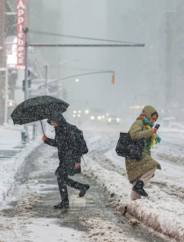Los peatones caminan por una calle mientras cae nieve durante una tormenta invernal en la ciudad de Nueva York.