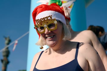 Una participante vestida con gorro de Santa Claus sonríe antes de saltar al agua del puerto de Barcelona.