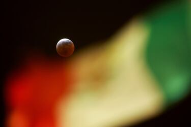 La bandera mexicana ondea mientras se observa una luna llena durante un eclipse lunar de "Luna de Sangre" desde Ciudad Juárez, México.