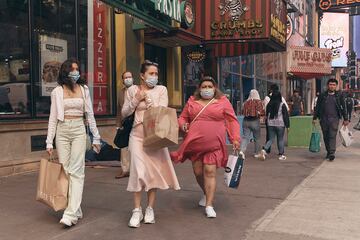 Un grupo de mujeres con mascarilla van de compras por las calles de Nueva York.