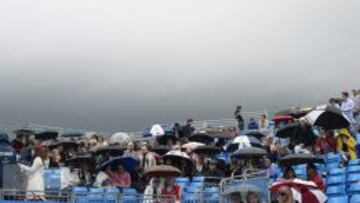 Los espectadores se protegen de la lluvia antes de que el partido fuera aplazado.. 