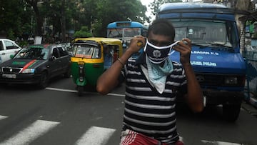 A police officer (unseen) gives a mask to a cyclist as part of an awareness campaign to control the spread of the of the COVID-19 coronavirus, in Kolkata on July 20, 2020. - Coronavirus cases in India passed one million on July 17, official data showed as