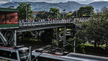 People wait in line on a bridge as they commute near a metro station on their way home before a curfew, amid the COVID 19 pandemic in Medellin, Colombia on March 31, 2021. - Authorities placed several regions including Antioquia department and its capital Medellin under a new lockdown after an increase in coronavirus cases. (Photo by JOAQUIN SARMIENTO / AFP)