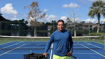 Fotografía de Yohny Romero con camiseta azul y short verde en una cancha de tenis azul.
