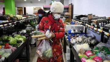 A woman wears a protective face mask as she shops in a market in Beijing on February 16, 2020. - The number of new cases from China&#039;s COVID-19 coronavirus epidemic dropped for a third consecutive day on February 16, as the World Health Organisation c