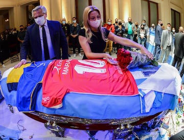 El presidente argentino Alberto Fernández (izq.) Y su compañera Fabiola Yáñez rindiendo homenaje al ataúd de la leyenda del fútbol argentino Diego Maradona en la capilla en llamas del palacio presidencial de la Casa Rosada 