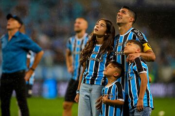 Gremio's Uruguayan forward Luis Suarez (R) and his children watch a video in his honour at the end of the Brazilian Championship football match between Gremio and Vasco da Gama at the Arena do Gremio stadium in Porto Alegre, Brazil, on December 3, 2023. Uruguay's 36-year-old record goalscorer Luis Suarez plays his last home game for Gremio on Sunday against Vasco da Gama and will be playing his very last game for this team on December 6 against Fluminense at Maracana stadium. (Photo by SILVIO AVILA / AFP)