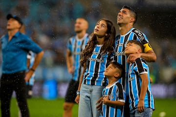 Gremio's Uruguayan forward Luis Suarez (R) and his children watch a video in his honour at the end of the Brazilian Championship football match between Gremio and Vasco da Gama at the Arena do Gremio stadium in Porto Alegre, Brazil, on December 3, 2023. Uruguay's 36-year-old record goalscorer Luis Suarez plays his last home game for Gremio on Sunday against Vasco da Gama and will be playing his very last game for this team on December 6 against Fluminense at Maracana stadium. (Photo by SILVIO AVILA / AFP)