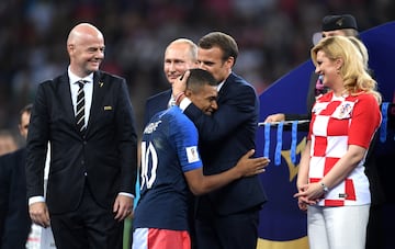El presidente francés, Emmanuel Macron abraza y otorga a Kylian Mbappé el Premio al Jugador Joven de la FIFA. Tras ellos el presidente de Rusia, Vladimir Putin, y la presidenta de Croacia, Kolinda Grabar Kitarovic. La fotografía fue tomada durante la final del Mundial de 2018.